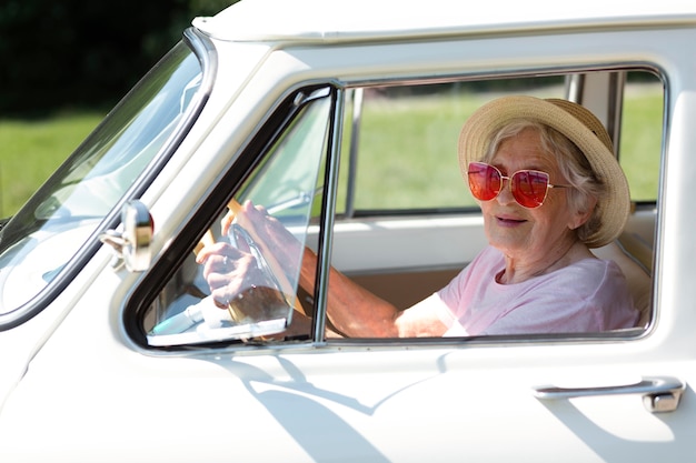Ältere Reisende mit roter Sonnenbrille neben ihrem Auto her