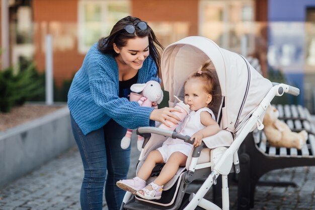 Ältere Schwester, die mit ihrer kleinen süßen Schwester draußen spaziert, gibt Wasser von ihr