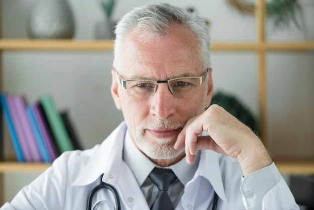 Älterer Doktor, der im Büro denkt