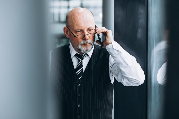 Älterer Geschäftsmann, der am Telefon im Büro spricht