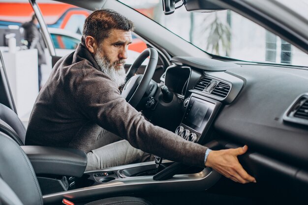 Älterer Geschäftsmann, der ein Auto im Autohaus wählt