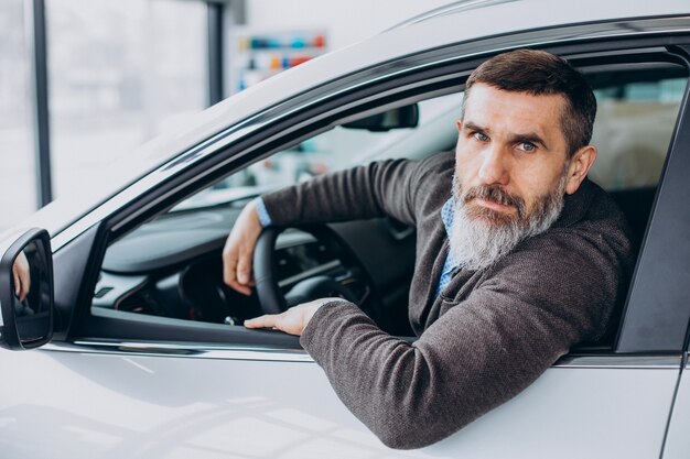 Älterer Geschäftsmann, der ein Auto im Autohaus wählt