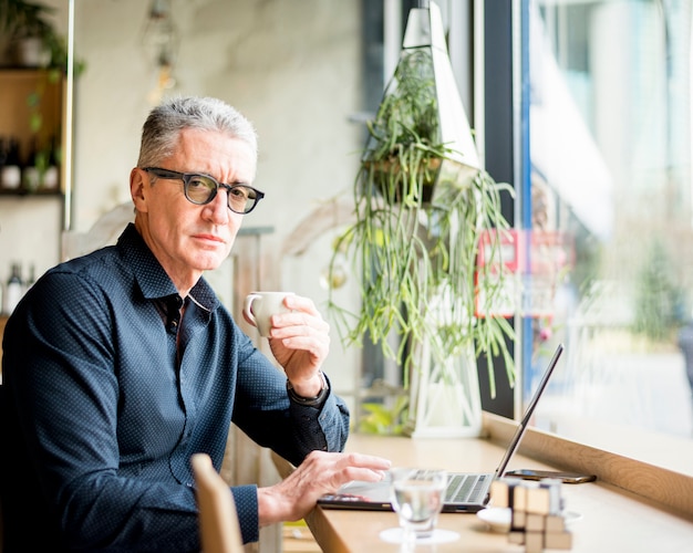 Älterer Geschäftsmann, der mit Kaffee aufwirft