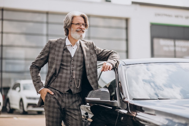 Älterer Geschäftsmann in einem Autohaus, der ein Auto wählt