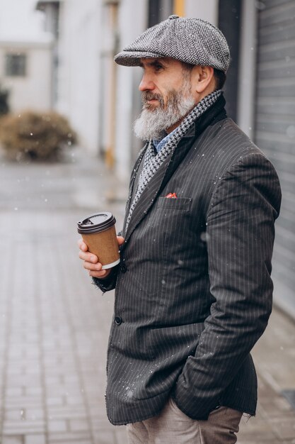 Älterer gutaussehender Mann, der Kaffee außerhalb der Straße trinkt