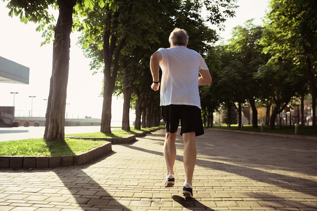 Älterer Mann als Läufer mit Armbinde oder Fitness-Tracker an der Stadtstraße
