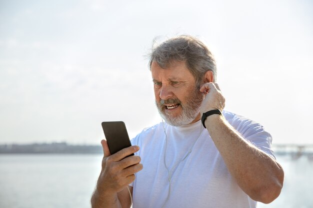 Älterer Mann als Läufer mit Fitness-Tracker am Flussufer.