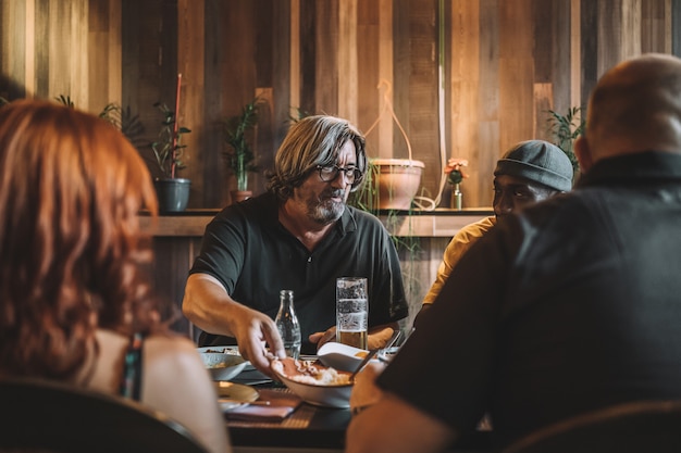 Älterer Mann beim Essen mit seinen Freunden in einem Restaurant