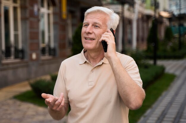 Älterer Mann, der auf Smartphone spricht, während draußen in der Stadt