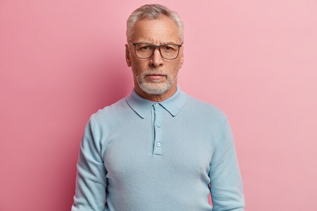 Älterer Mann, der blaues Hemd und trendige Brillen trägt