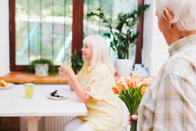 Älterer Mann, der dem Geliebten Blumen geben wird