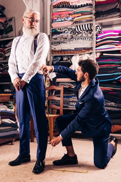 Älterer Mann, der den männlichen Modedesigner misst seine Hose im Shop betrachtet