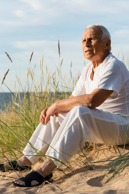 Älterer Mann, der die Aussicht am Strand genießt