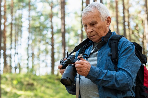 Älterer Mann, der draußen mit Kamera reist