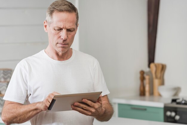 Älterer Mann, der eine Tablette mit Kopienraum hält