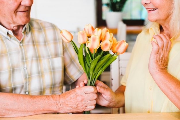 Älterer Mann der Ernte, der Blumenstrauß Frau darstellt