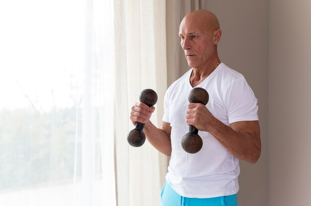 Älterer Mann, der Fitnesshanteln benutzt