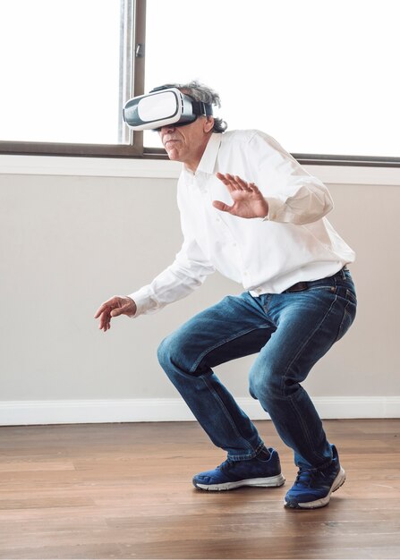 Älterer Mann, der im Raum erfährt virtuelle Realität steht