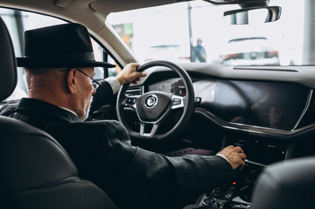 Älterer Mann, der innerhalb eines Autos sitzt