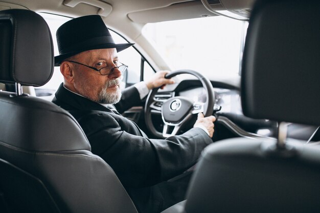 Älterer Mann, der innerhalb eines Autos sitzt