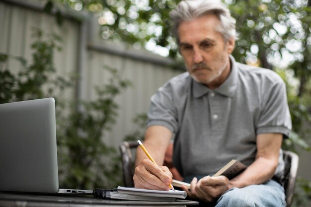 Älterer Mann, der Online-Kurse auf einem Laptop macht