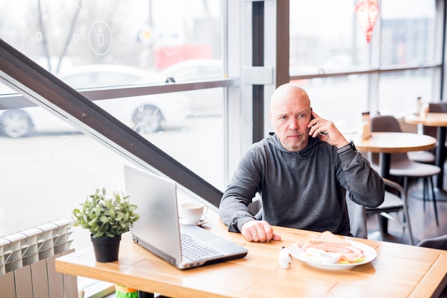 Älterer Mann, der per Telefon spricht