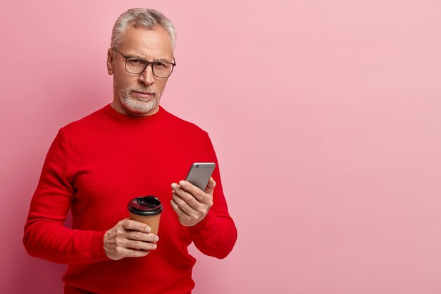 Älterer Mann, der roten Pullover und trendige Brillen trägt