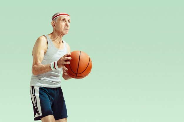 Älterer Mann, der Sportkleidung trägt, die Basketball auf Grün spielt