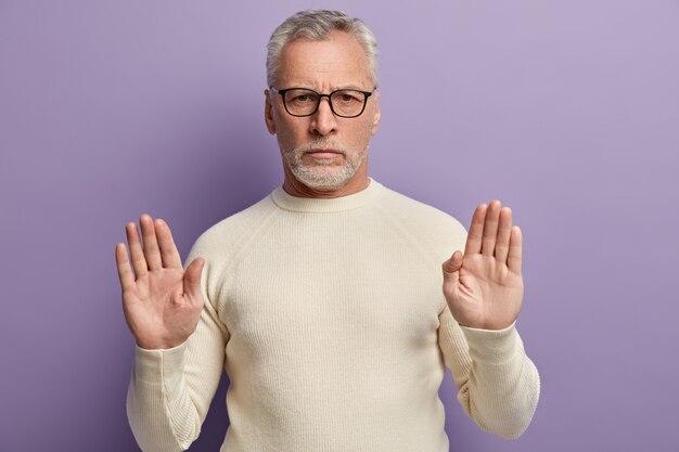 Älterer Mann, der weißen Pullover und trendige Brillen trägt