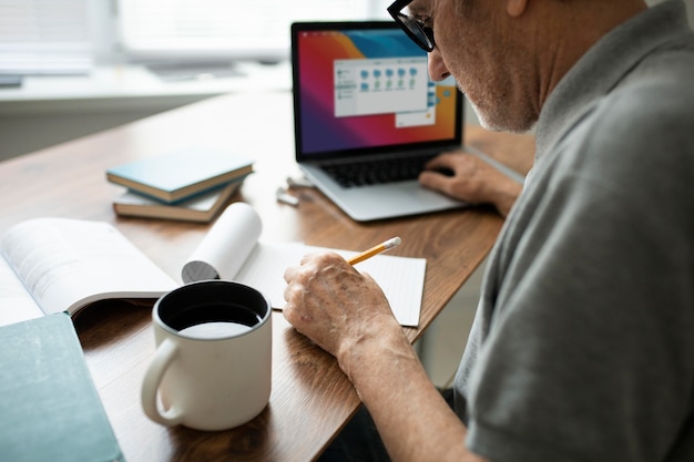 Älterer Mann, der zu Hause Online-Kurse auf einem Laptop macht