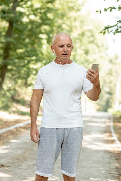 Älterer Mann des mittleren Schusses, der sein Telefon cheking ist