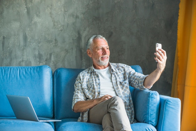 Älterer Mann im Ruhestand, der selfie durch Mobiltelefon nimmt