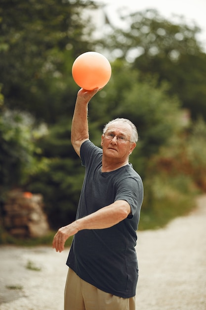 Älterer Mann im Sommerpark. Grangfather mit einem Ball.