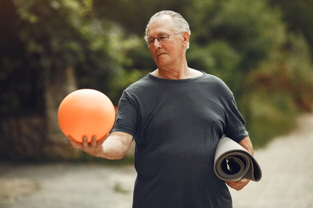 Älterer Mann im Sommerpark. Grangfather mit einem Ball.