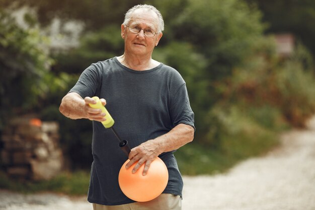 Älterer Mann im Sommerpark. Grangfather mit einer Pballpumpe.