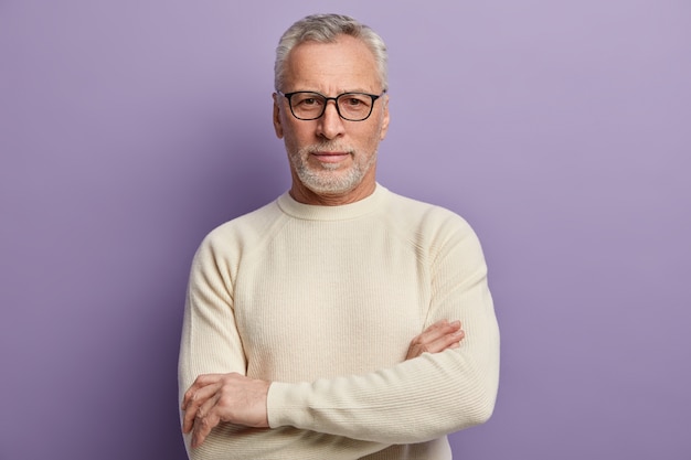 Älterer Mann im weißen Pullover und in den Brillen