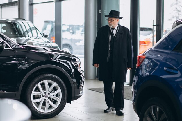 Älterer Mann in einem Autosalon, der ein Auto wählt