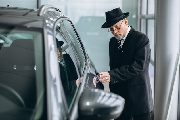 Älterer Mann in einem Autosalon, der ein Auto wählt