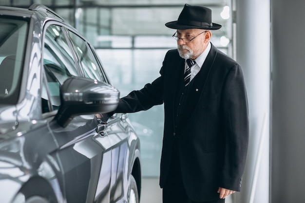 Älterer Mann in einem Autosalon, der ein Auto wählt