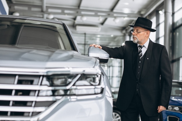 Älterer Mann in einem Autosalon, der ein Auto wählt