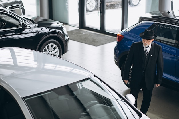 Älterer Mann in einem Autosalon, der ein Auto wählt