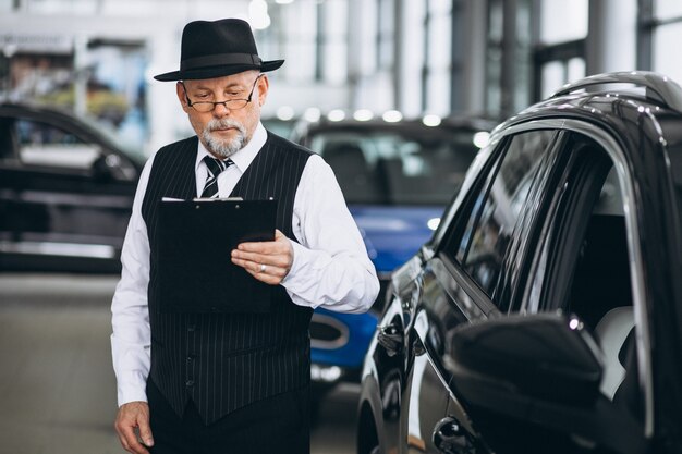 Älterer Mann in einem Autosalon, der ein Auto wählt