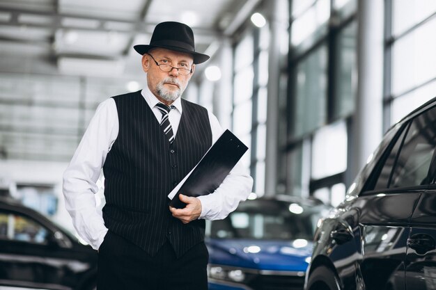 Älterer Mann in einem Autosalon, der ein Auto wählt