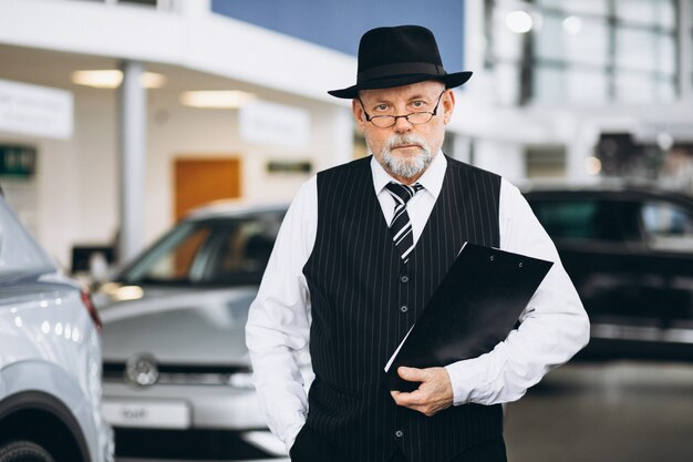 Älterer Mann in einem Autosalon, der ein Auto wählt