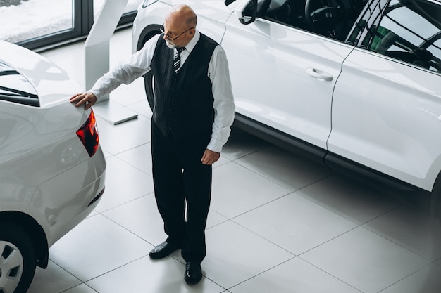 Älterer Mann in einem Autosalon, der ein Auto wählt