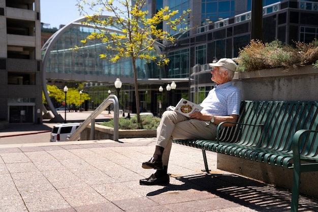 Älterer Mann liest Buch auf Bank im Freien
