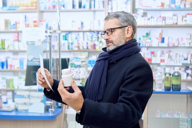 Älterer Mann liest Rezept in der Apotheke