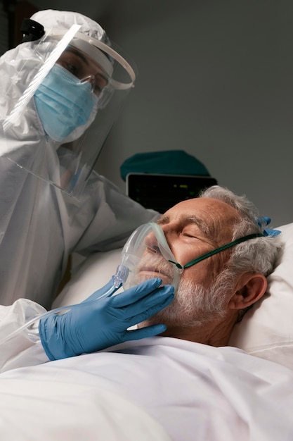 Älterer Mann mit Beatmungsgerät neben Ärzten