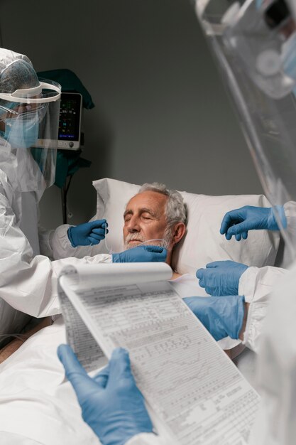 Älterer Mann mit Beatmungsgerät neben Ärzten