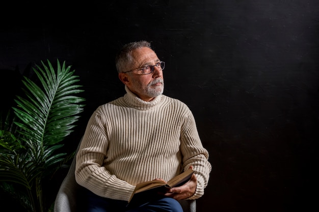 Älterer Mann mit dem Buch, das weg schaut